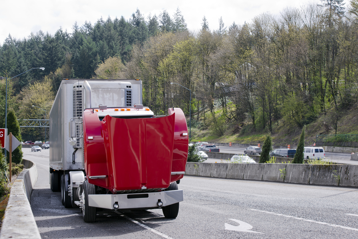 Broken on the road red semi truck with an open hood